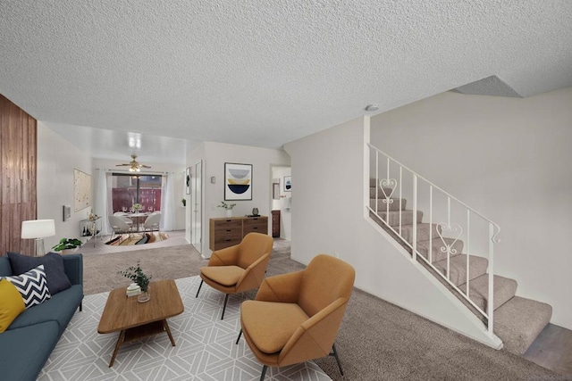 carpeted living room featuring ceiling fan and a textured ceiling