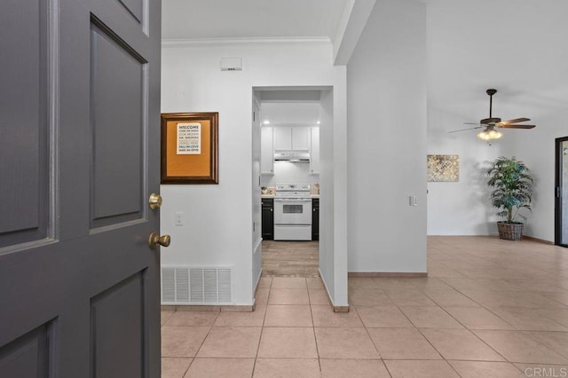 foyer entrance featuring ceiling fan, crown molding, and light tile patterned floors