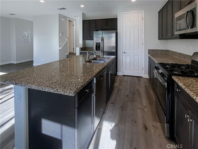 kitchen with appliances with stainless steel finishes, sink, an island with sink, and wood-type flooring