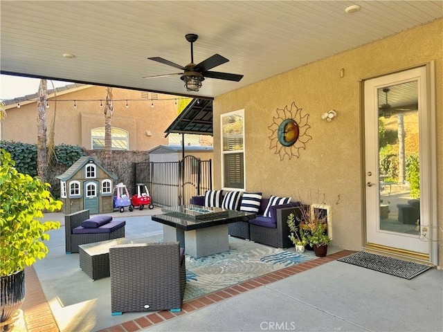 view of patio featuring an outdoor structure, an outdoor living space with a fire pit, and ceiling fan