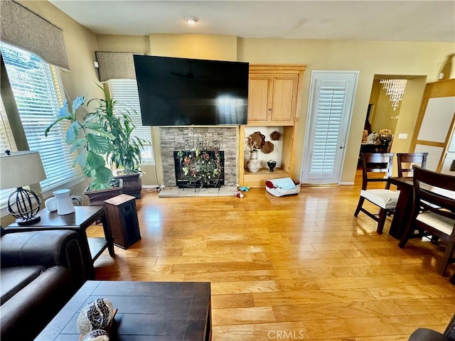 living room with light hardwood / wood-style flooring, plenty of natural light, and a stone fireplace