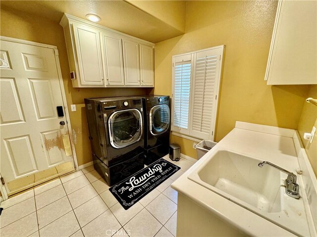 laundry room featuring sink, washer and clothes dryer, cabinets, and light tile patterned flooring