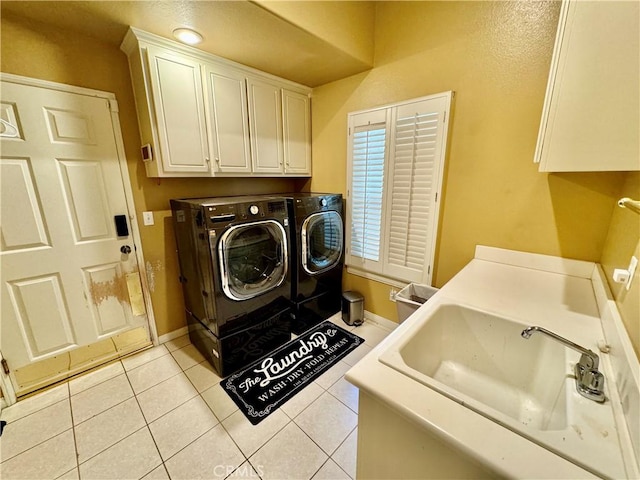 clothes washing area featuring sink, light tile patterned flooring, separate washer and dryer, and cabinets