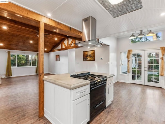 kitchen with black gas range, white cabinetry, hardwood / wood-style floors, island exhaust hood, and french doors