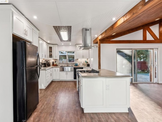 kitchen featuring white cabinets, black refrigerator, island exhaust hood, tasteful backsplash, and sink