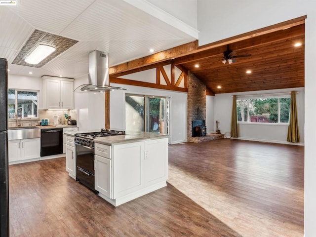 kitchen featuring a wood stove, white cabinets, black appliances, and island range hood