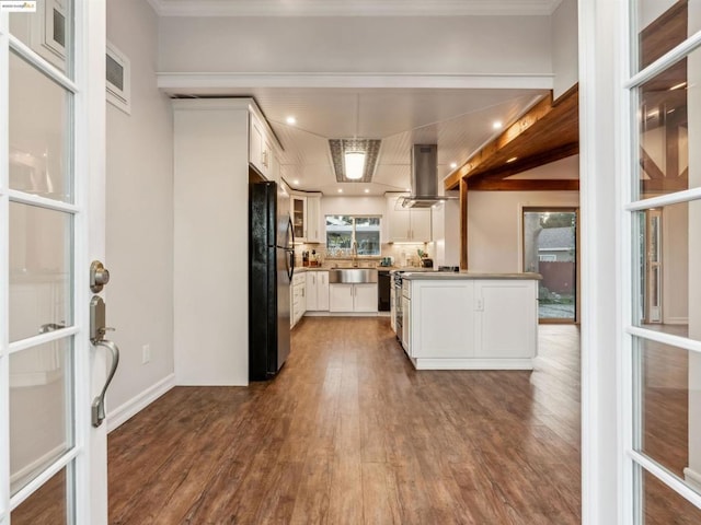 kitchen featuring wall chimney exhaust hood, white cabinetry, sink, dark hardwood / wood-style floors, and black fridge