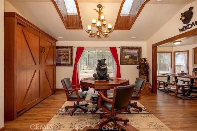 dining space with an inviting chandelier, wood-type flooring, and lofted ceiling with skylight