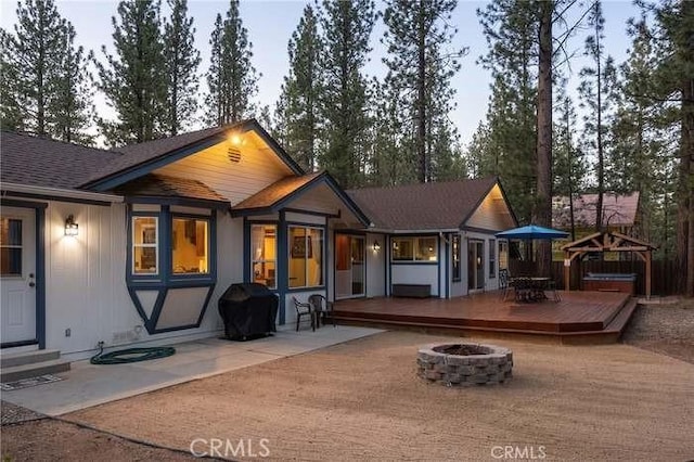 back house at dusk with a deck and an outdoor fire pit