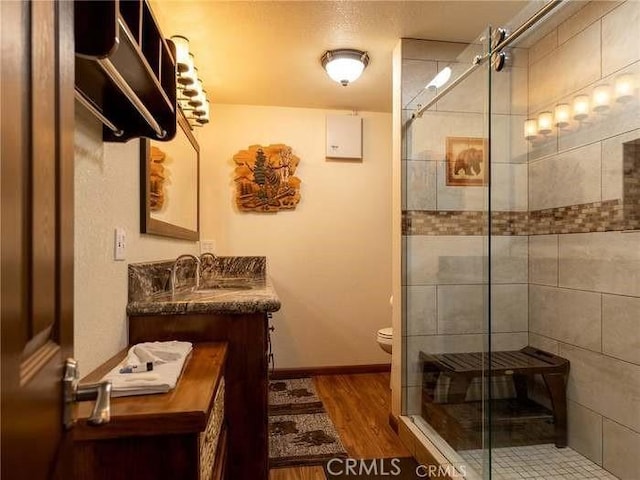 bathroom with toilet, vanity, walk in shower, and hardwood / wood-style flooring