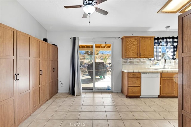 kitchen featuring tile countertops, ceiling fan, backsplash, dishwasher, and sink