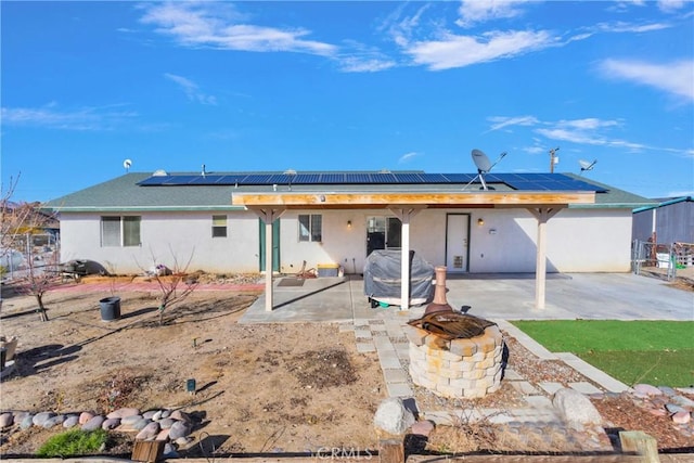 back of house with solar panels, a fire pit, and a patio