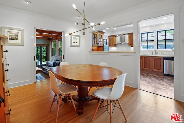 dining area with a healthy amount of sunlight, light wood-type flooring, crown molding, and a chandelier