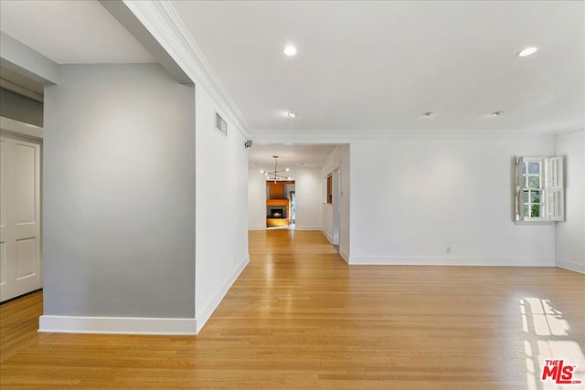 hall with crown molding, a chandelier, and light wood-type flooring