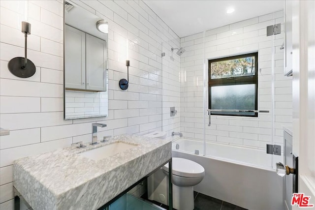 full bathroom with toilet, tile walls, tiled shower / bath, and vanity