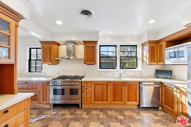 kitchen featuring appliances with stainless steel finishes, backsplash, ornamental molding, wall chimney exhaust hood, and sink