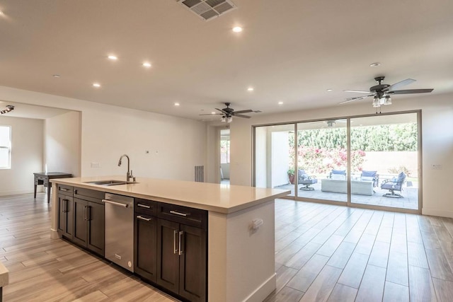 kitchen featuring a kitchen island with sink, dishwasher, sink, and light hardwood / wood-style flooring