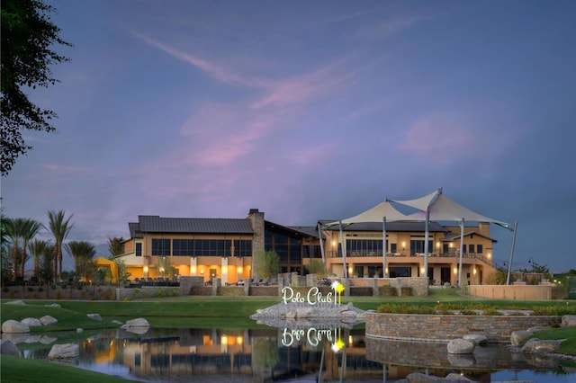 back house at dusk with a water view and a yard