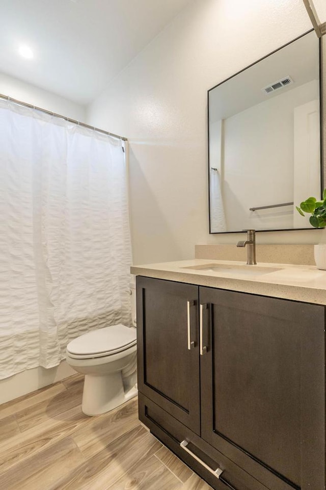 full bathroom featuring toilet, shower / tub combo, wood-type flooring, and vanity