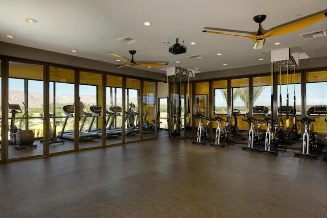 exercise room featuring ceiling fan, a wealth of natural light, and a mountain view