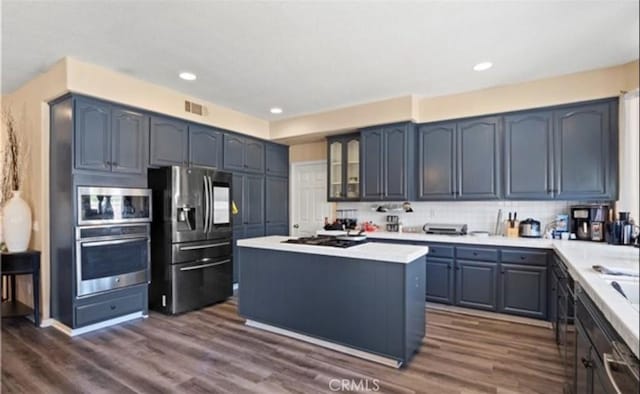 kitchen featuring decorative backsplash, dark wood-type flooring, a center island, and stainless steel appliances