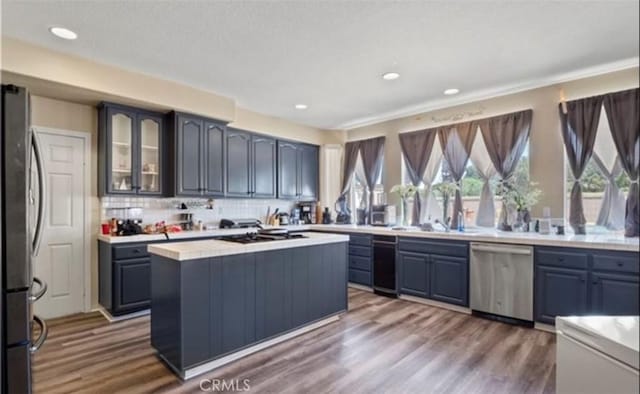 kitchen featuring hardwood / wood-style floors, stainless steel appliances, backsplash, and a kitchen island