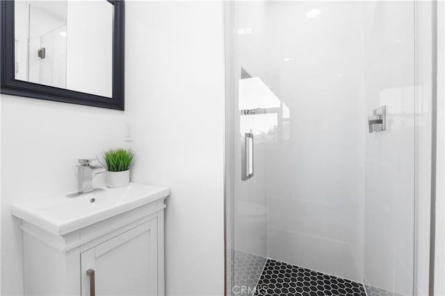 bathroom featuring a shower with shower door and vanity