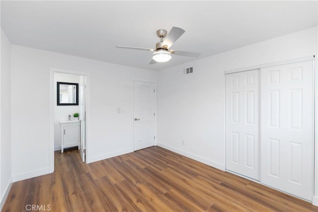 unfurnished bedroom with ceiling fan, a closet, and dark hardwood / wood-style flooring