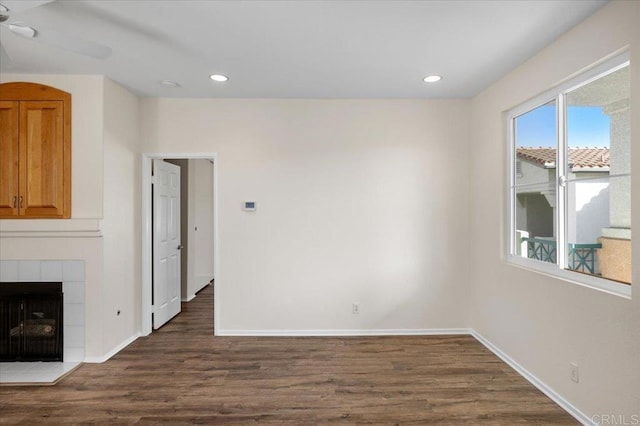 interior space with dark wood-type flooring, ceiling fan, and a tile fireplace