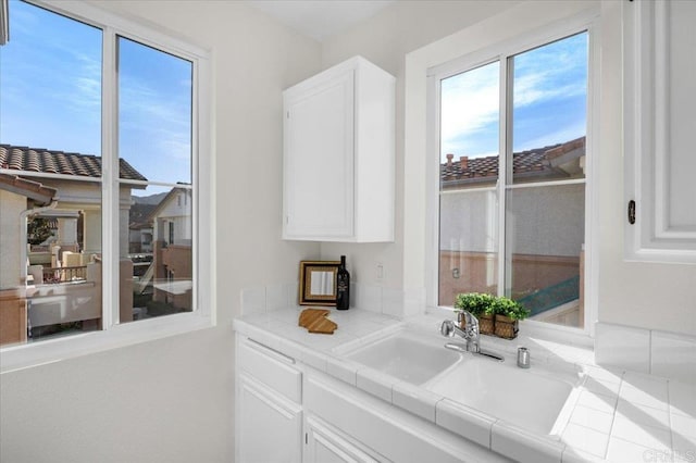 kitchen featuring white cabinetry, sink, and tile counters