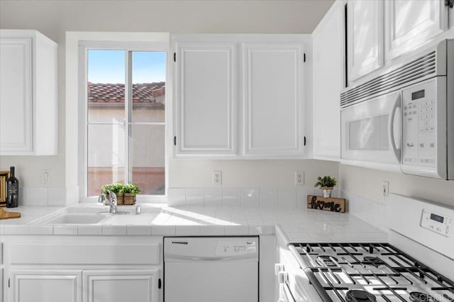 kitchen with white appliances, white cabinets, and tile countertops