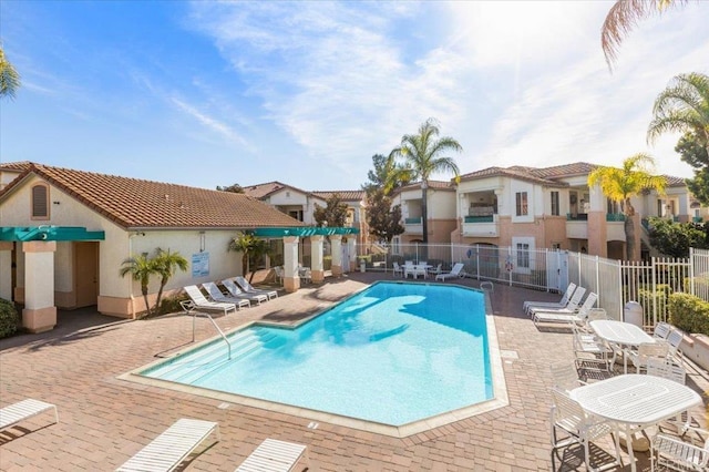 pool with a patio, fence, and a residential view