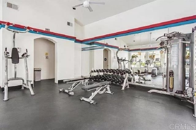 gym with arched walkways, a high ceiling, visible vents, and a ceiling fan