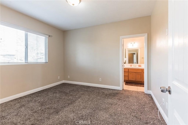 unfurnished bedroom with ensuite bathroom and light colored carpet