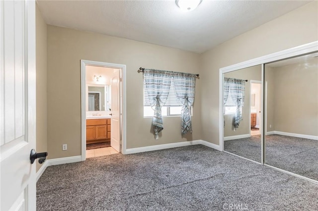 unfurnished bedroom featuring light carpet, a closet, and ensuite bath