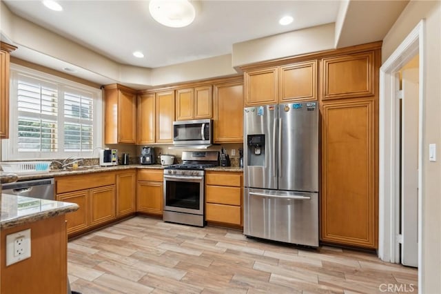 kitchen featuring sink, stainless steel appliances, and light stone countertops