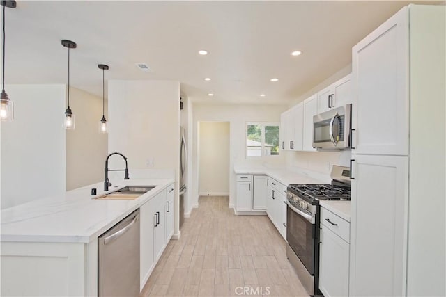 kitchen featuring pendant lighting, kitchen peninsula, sink, white cabinetry, and stainless steel appliances