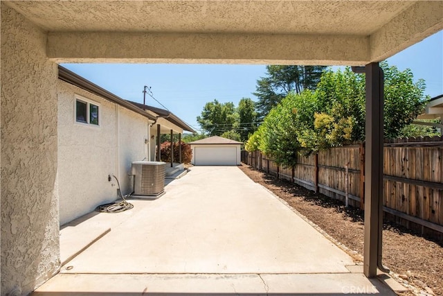 view of patio featuring a garage, central air condition unit, and an outbuilding