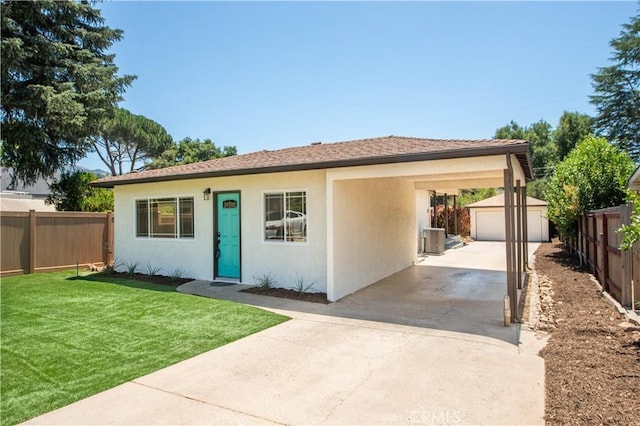 view of front of house with a front yard, an outbuilding, a carport, central AC unit, and a garage