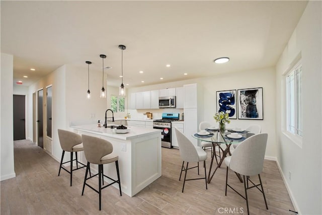 kitchen with decorative light fixtures, a kitchen bar, kitchen peninsula, white cabinetry, and stainless steel appliances