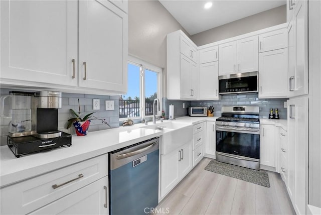 kitchen featuring decorative backsplash, appliances with stainless steel finishes, and white cabinetry