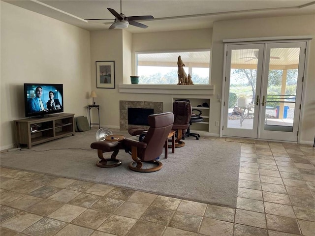 interior space with ceiling fan, a tiled fireplace, and french doors