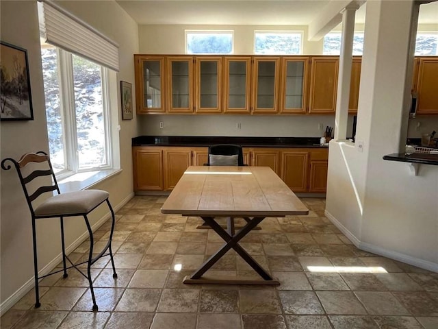 kitchen with a breakfast bar, decorative columns, and plenty of natural light