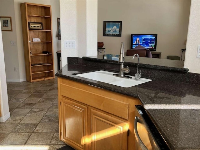 kitchen with dishwasher, dark stone countertops, and sink