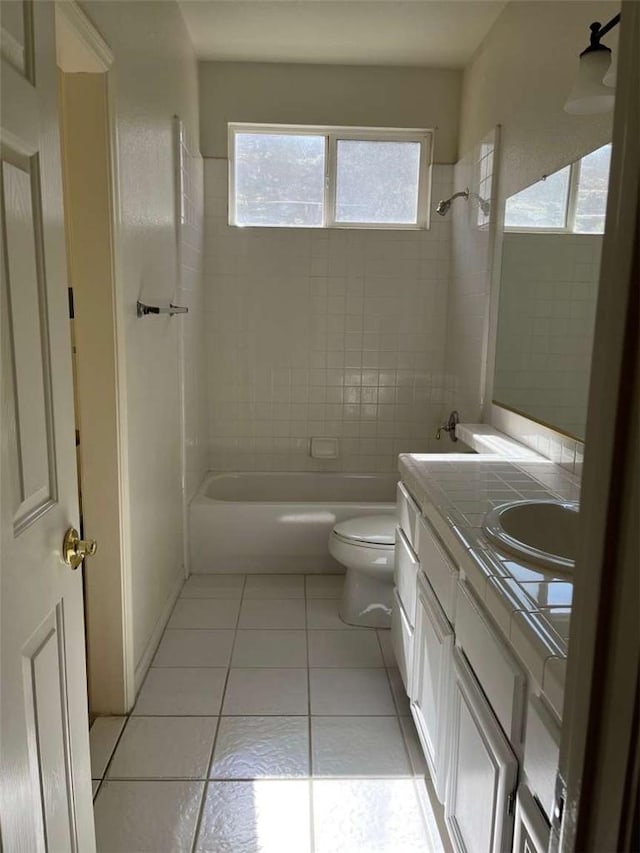 full bathroom featuring toilet, tile patterned floors, vanity, and tiled shower / bath combo