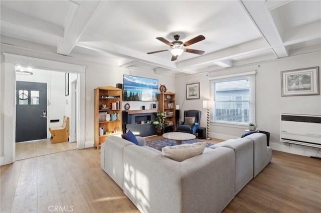 living room featuring heating unit, light hardwood / wood-style flooring, and beamed ceiling