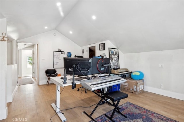 workout area featuring lofted ceiling and light wood-type flooring