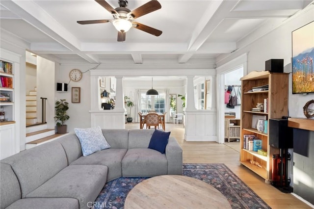 living room featuring built in shelves, beamed ceiling, light wood-type flooring, ceiling fan, and coffered ceiling