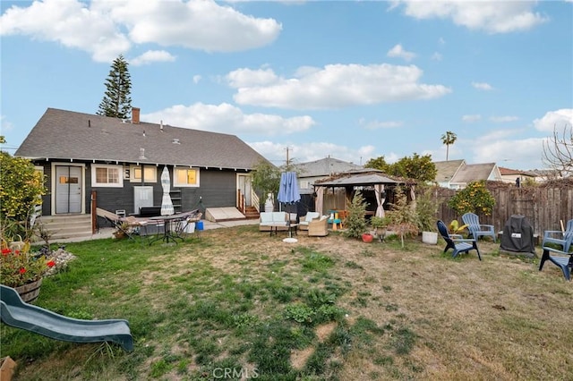 rear view of property featuring a gazebo and a lawn