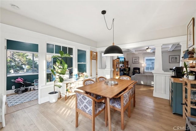 dining area featuring ceiling fan, light hardwood / wood-style flooring, beamed ceiling, and ornate columns